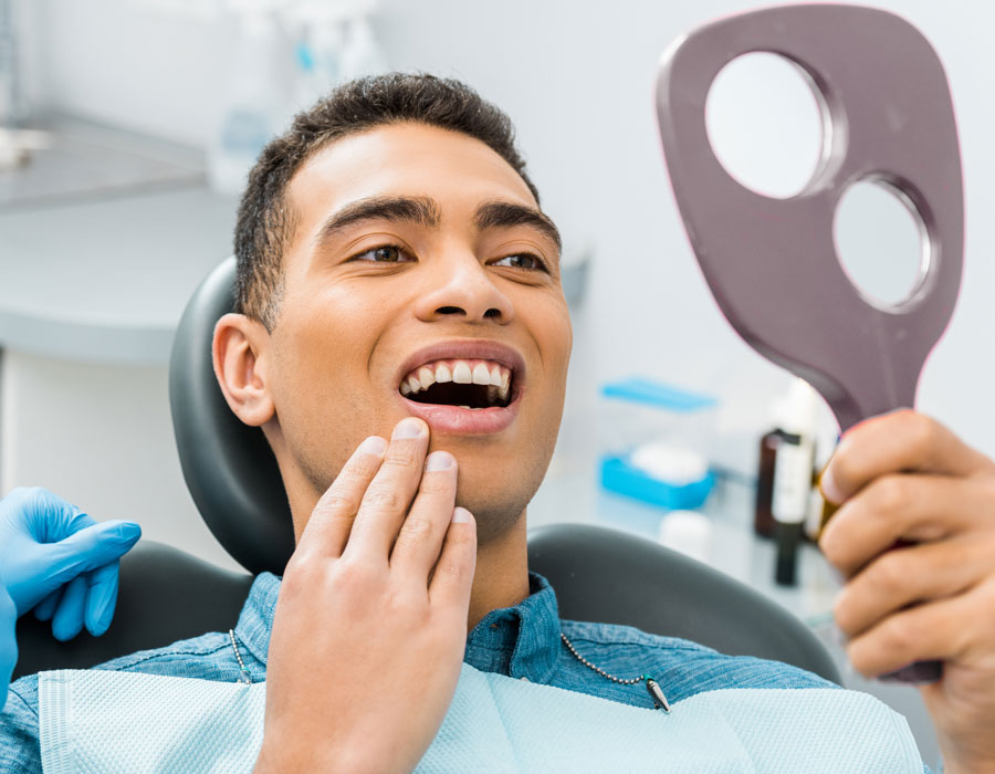 dental-patient-looking-in-the-mirror-after-gum-recession-treatment